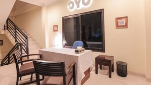 Zona de recepción de hotel con mostrador, escalera y un cuadro en la pared.