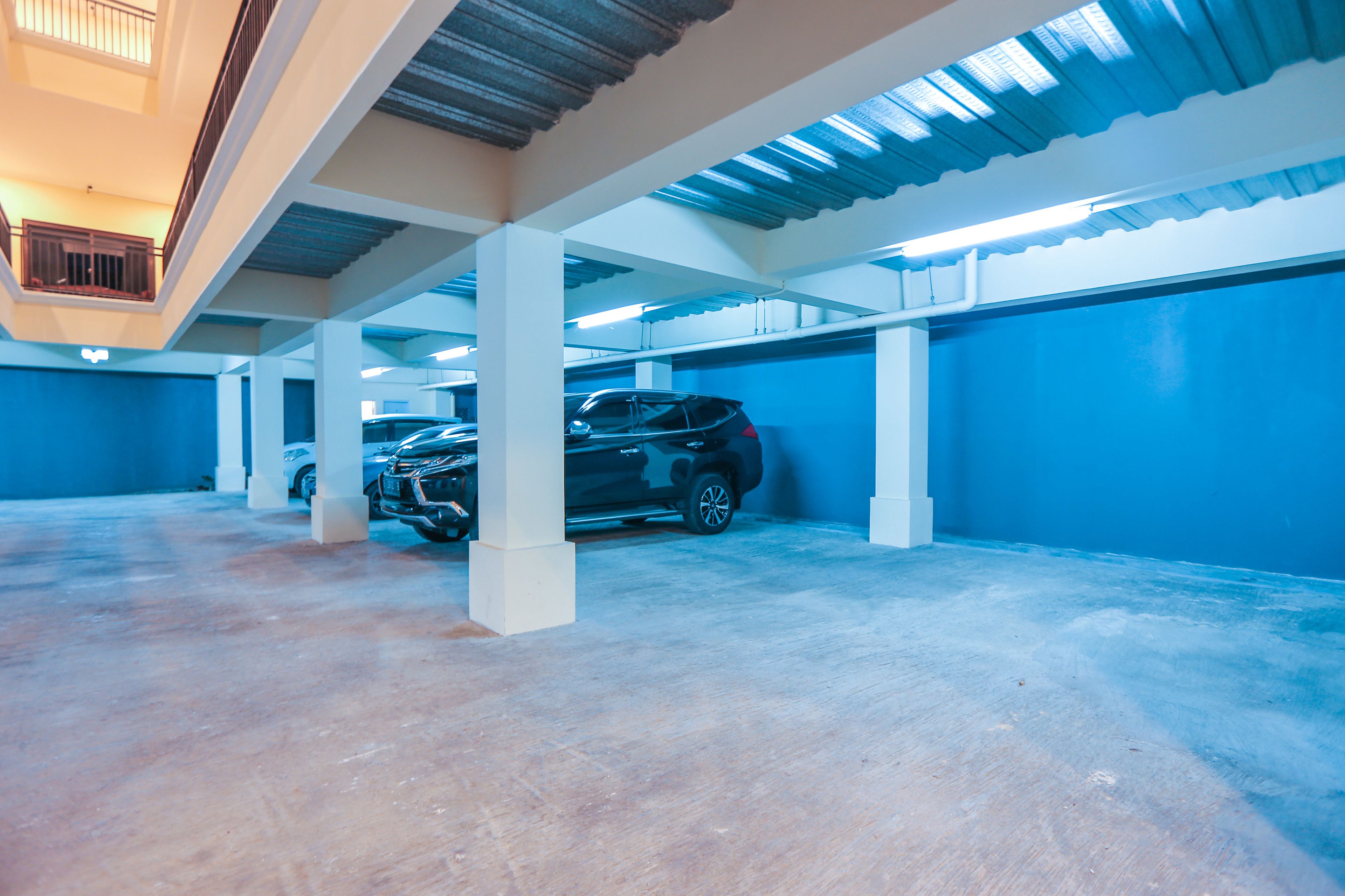 An indoor parking garage with concrete pillars and blue walls.