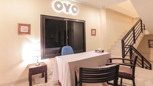 Zona de recepción de un hotel con un mostrador, un ventanal amplio y una escalera.