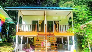 Um edifício de dois andares com varanda, escadaria e área externa coberta.