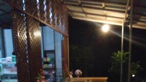 A covered outdoor seating area with a table and chairs, a patterned floor, and a view of the outside. - Ton Tawan resort (Ko Kood)