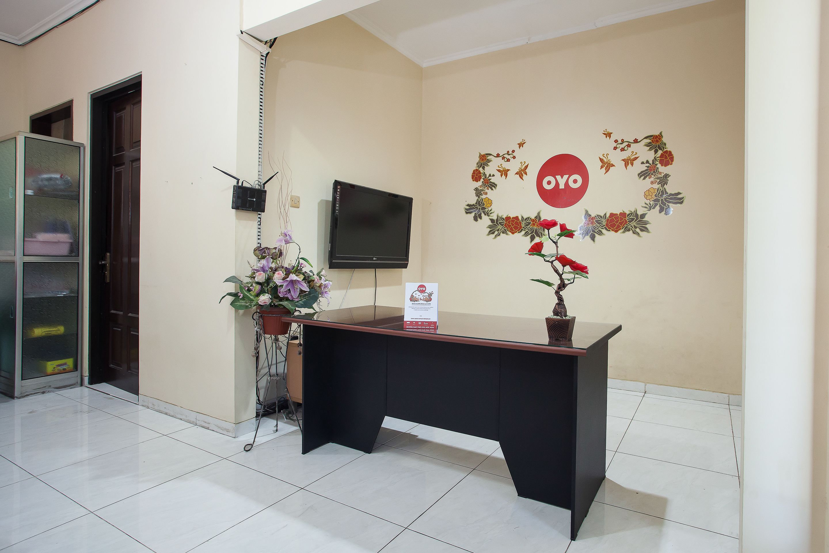 A reception desk with a television, a floral decoration, and a sign on the wall.