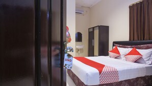 A hotel room with a bed, a wardrobe, a sink, and a door with a sign. - Hotel O Graha 99 (Surabaya)