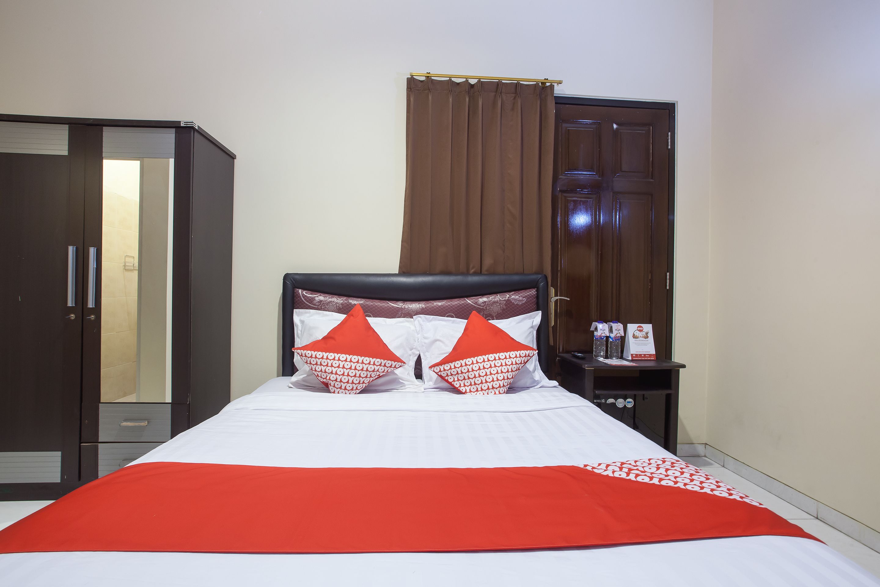 A hotel room with a bed, a wardrobe, a nightstand, and a curtain.