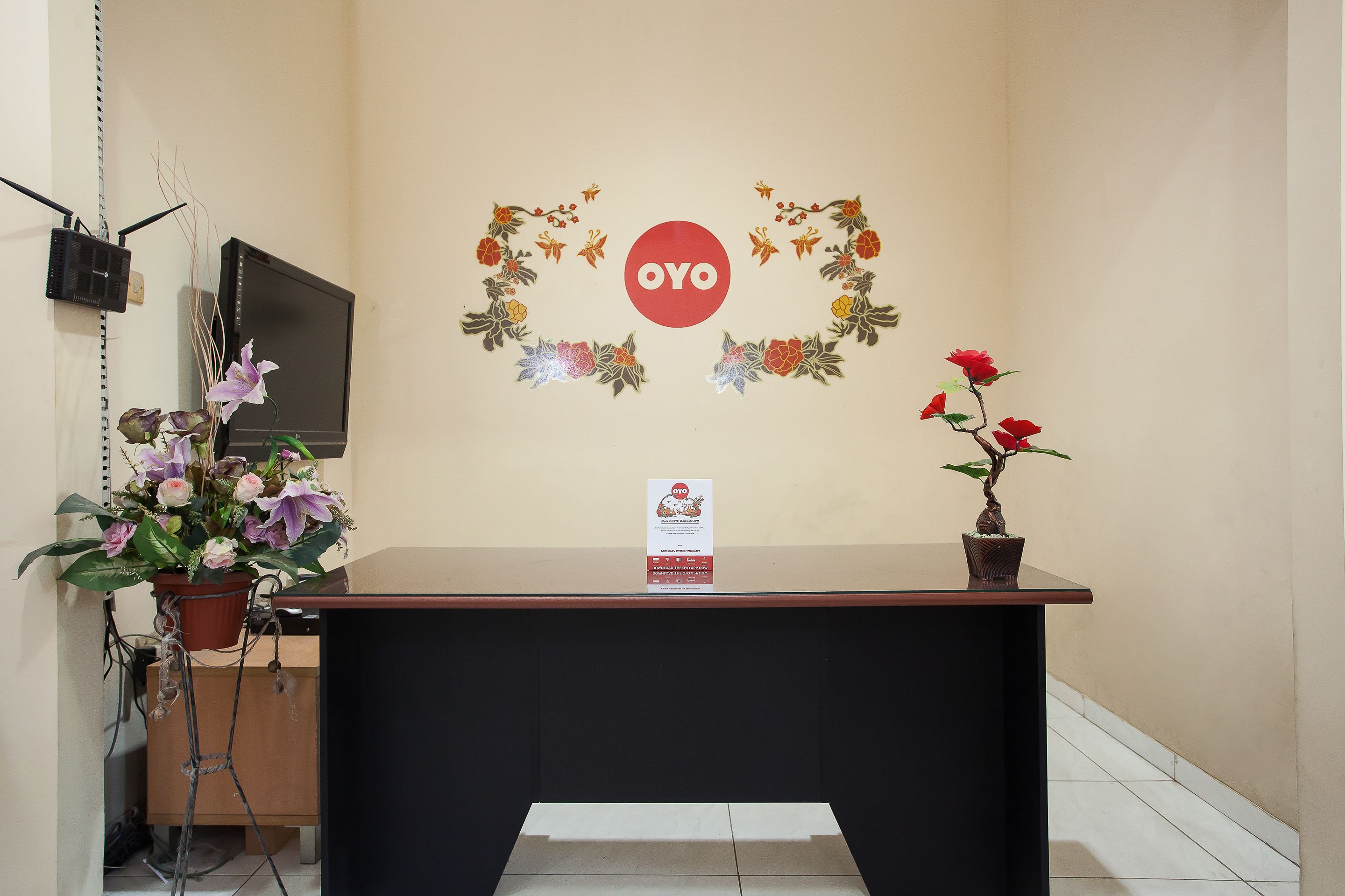 Un mostrador de recepción con un cartel que dice "OYO" rodeado de adornos florales.