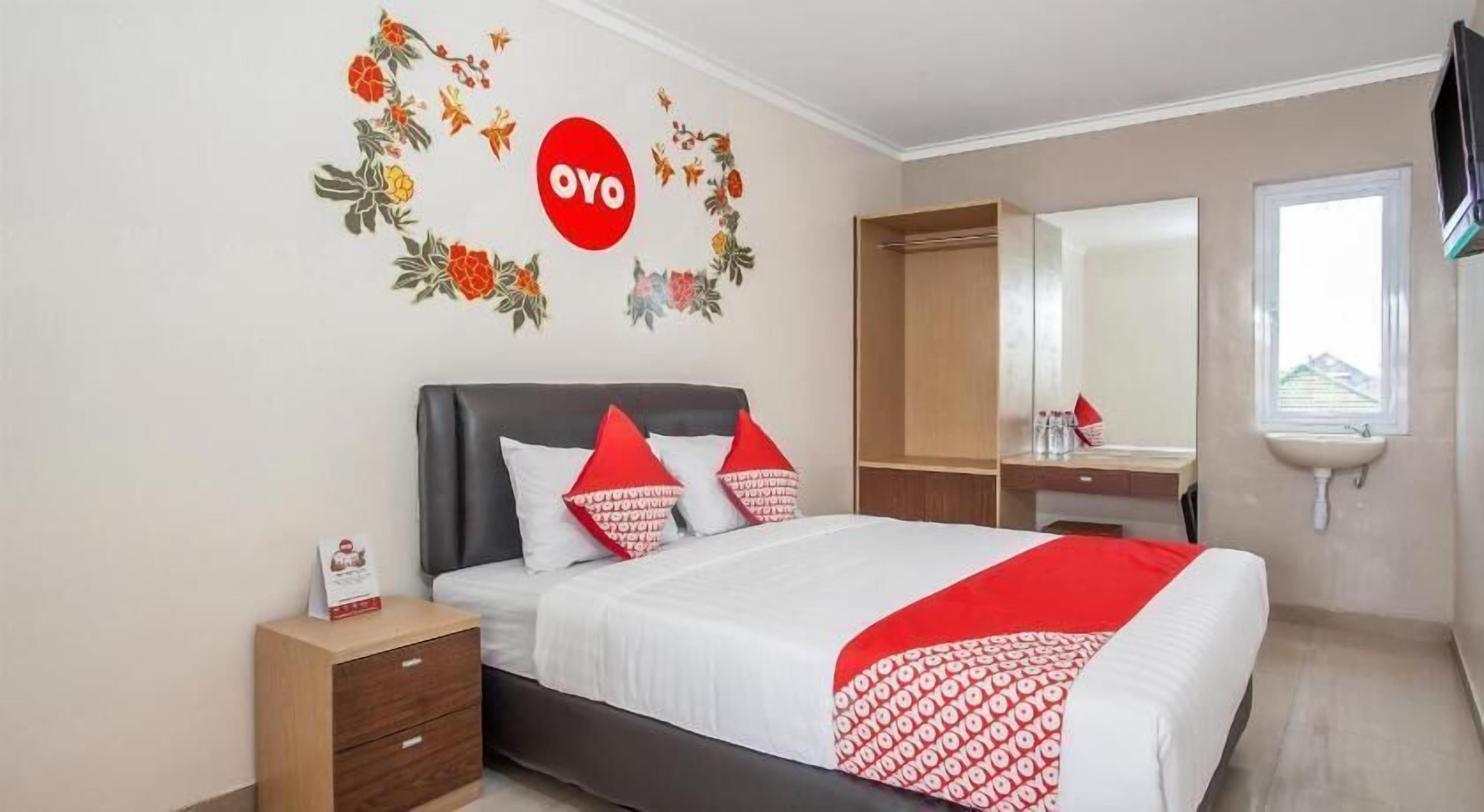 A hotel room with a bed, a nightstand, a wardrobe, a mirror, and a window.