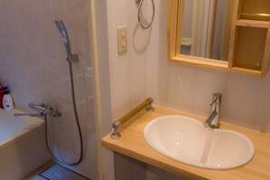A bathroom with a bathtub, a shower, a sink, and a mirror.