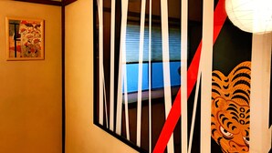 A room with a window, a framed picture on the wall, and a decorative mask on the right. - Yuenshe Nishi Hongan-Ji Villa (Kyoto)