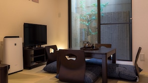 A living room with a flat-screen TV, a coffee table, and a sofa. There is a sliding glass door leading to a garden. - Yuenshe Nishi Hongan-Ji Villa (Kyoto)