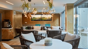 A modern interior with wicker furniture, a round table, and a large TV screen on the wall. - Mi-pad Queenstown (Queenstown)