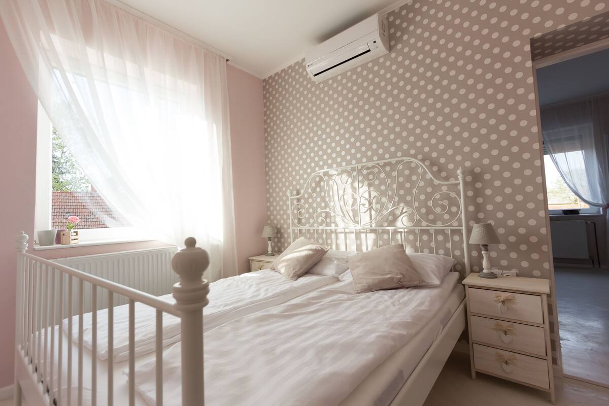 A bedroom with a bed, bedside tables, a nightstand, and a window with curtains.