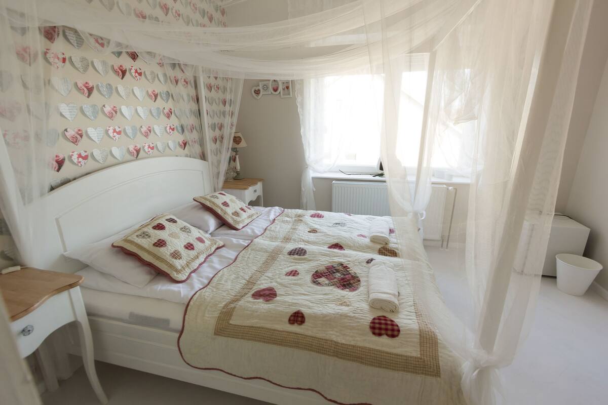 A neatly made bed with a quilt, a bedside table, and a nightstand.