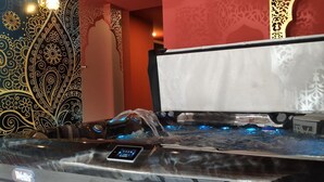 A hot tub with a control panel, surrounded by ornate wall designs.