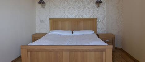 A wooden bed with a headboard, two bedside tables, and a patterned wallpaper.