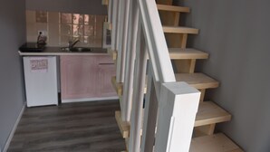 A staircase with wooden steps and a handrail, leading to a kitchen area with a sink and cabinets.