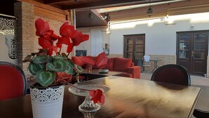 An outdoor patio area with a wooden table, red chairs, and a potted plant.