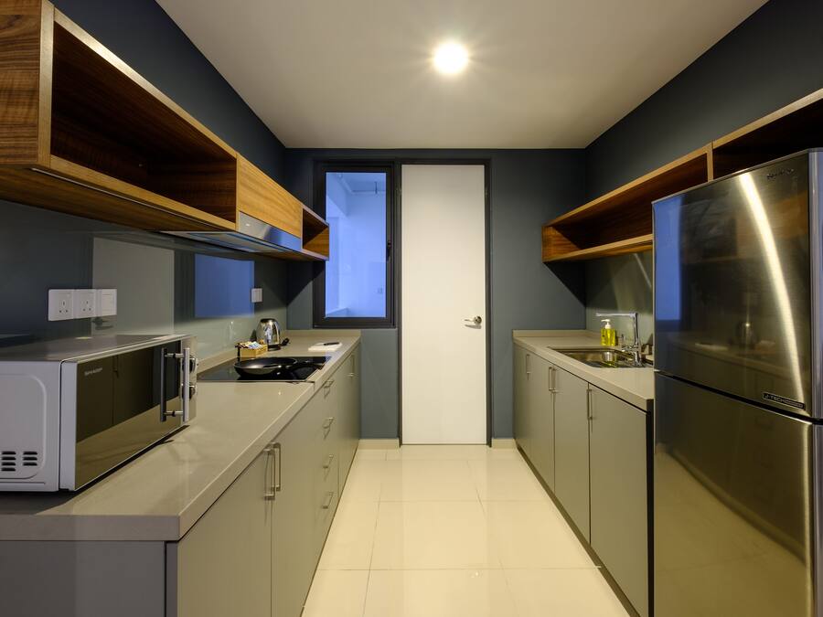 Una cocina compacta con electrodomésticos modernos, armarios superiores de madera y vistas a través de la puerta.