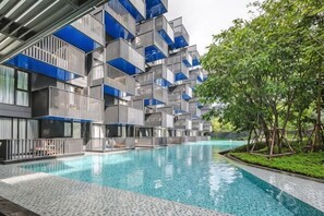 Ein modernes Gebäude mit Swimmingpool, Balkonen und Grünflächen.