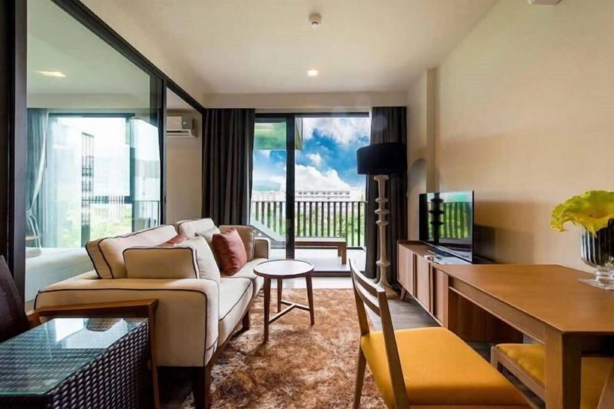 Een moderne hotelkamer met een bank, een klein rond tafeltje, een eettafel en een televisie.