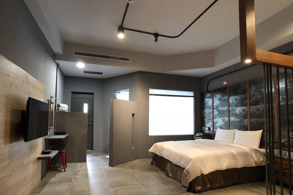 Une chambre d’hôtel moderne, dotée d’un grand lit, d’un bureau et d’une télévision.