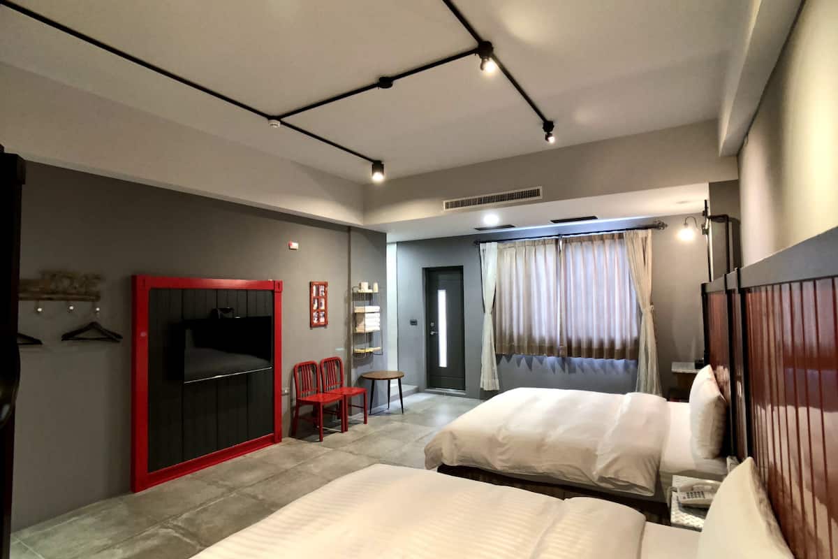 Une chambre d’hôtel avec deux lits, une armoire, un bureau et un espace douche.