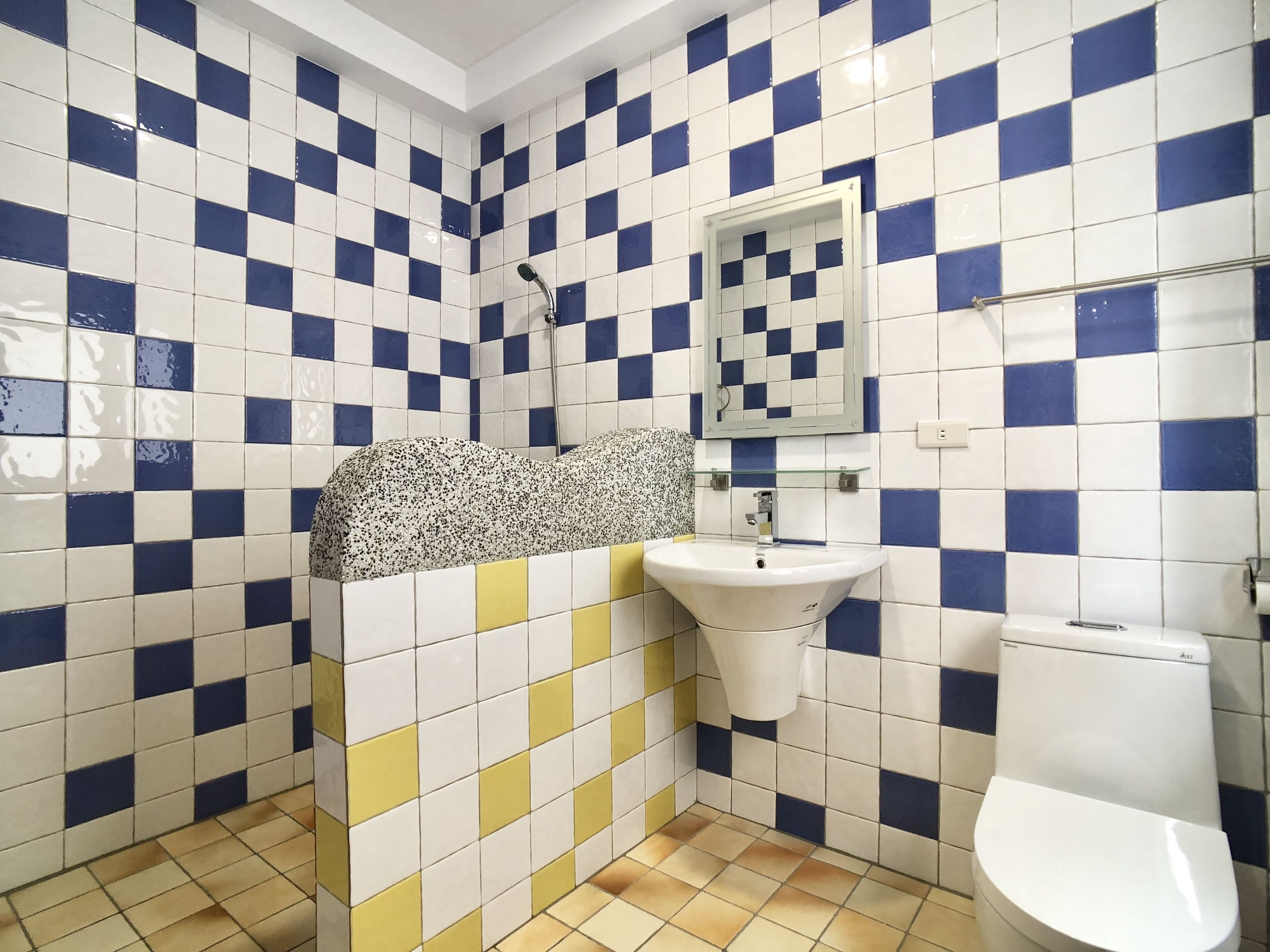 A bathroom with a checkered tile pattern, a sink, a toilet, and a shower.