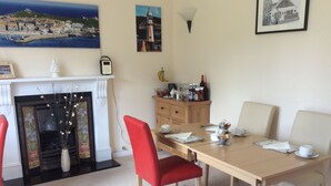 Uma sala de jantar com mesa de madeira, cadeiras vermelhas e lareira.