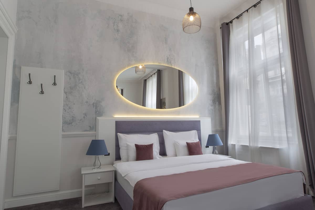 Un dormitorio moderno con una cama grande, un espejo redondo, lámparas de noche y un armario.