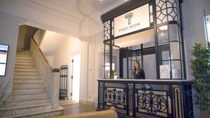 A reception area with a staircase, a reception desk, and a potted plant. - Public House Hotel (Belgrade)