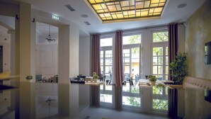 A spacious room with a large window, a ceiling light fixture, and a seating area with a sofa and chairs. - Public House Hotel (Belgrade)