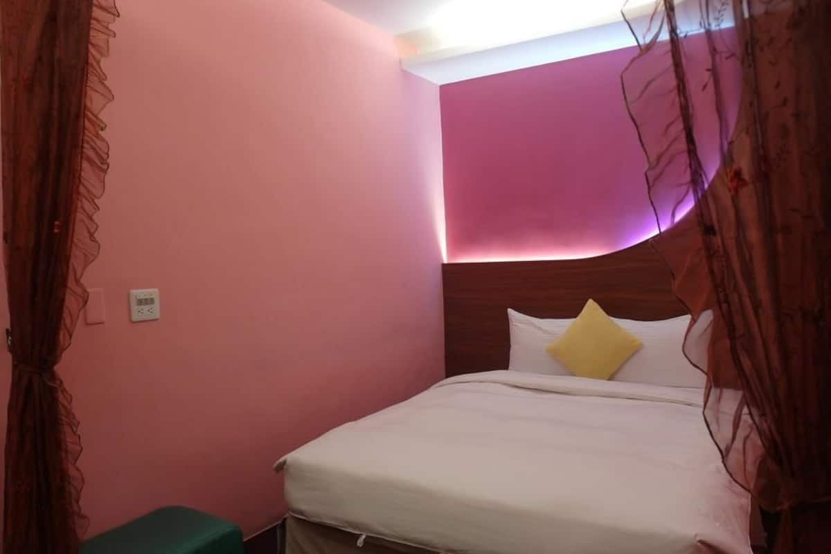 A bedroom with a bed, a bedside table, and a wall-mounted light.