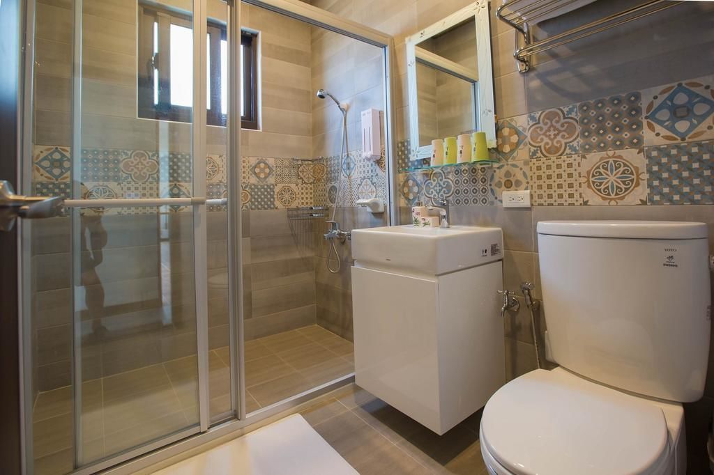 Une salle de bain avec une douche à parois de verre, des toilettes blanches et un lavabo avec un miroir au-dessus.