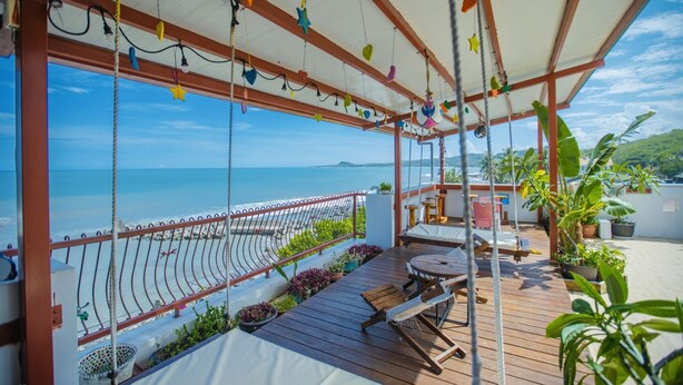 A covered outdoor area with a wooden deck, a metal railing, and a view of the sea. - Najie (Donghe)