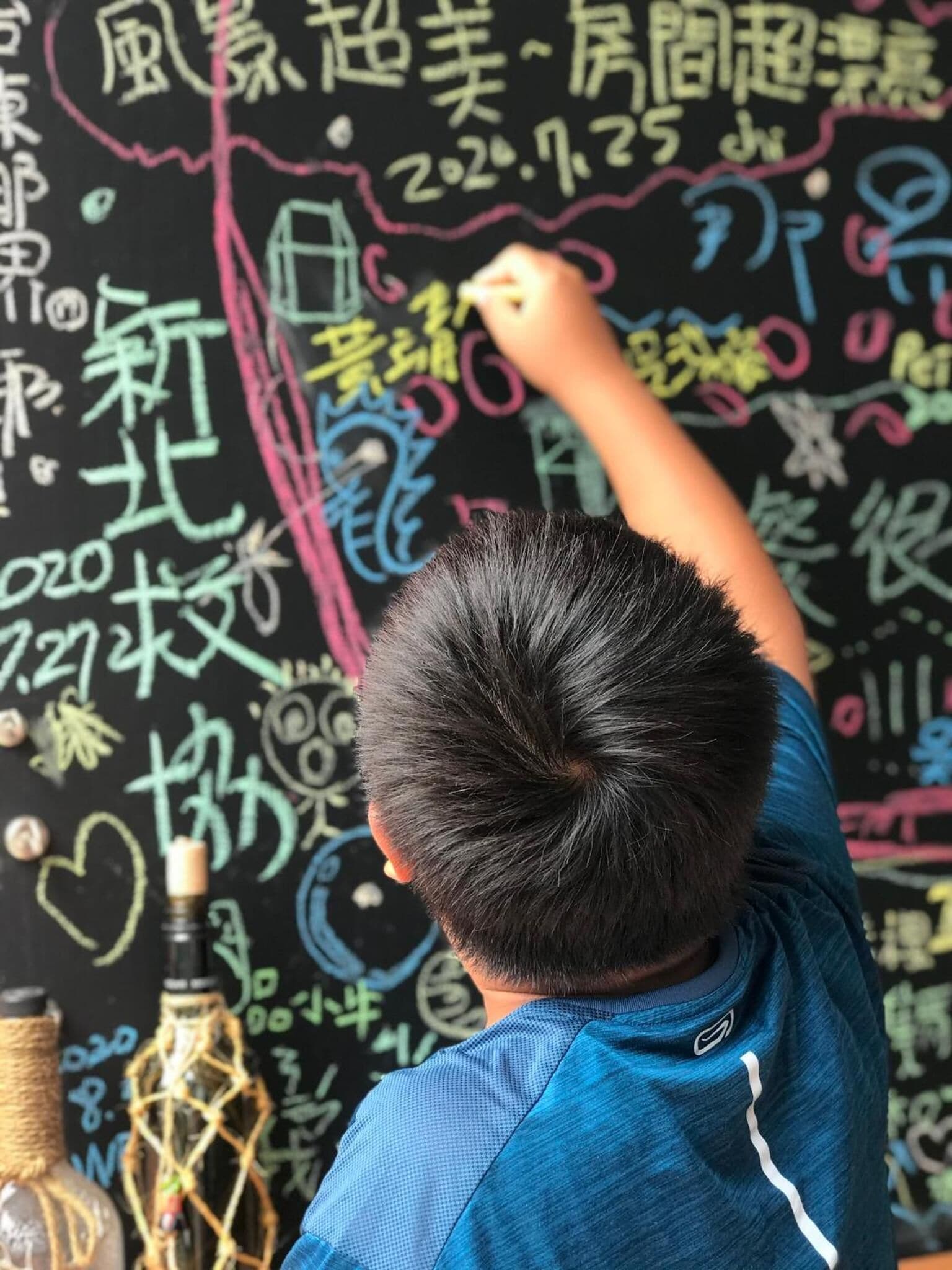 A child writing on a blackboard with colorful chalk.