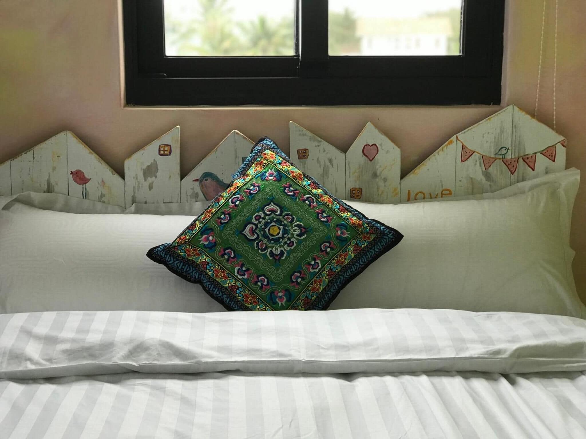 A bed with a striped pillow and a colorful decorative pillow.