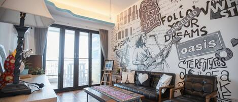 Un salon avec une grande fresque murale, un canapé, une table basse et un ventilateur de plafond.