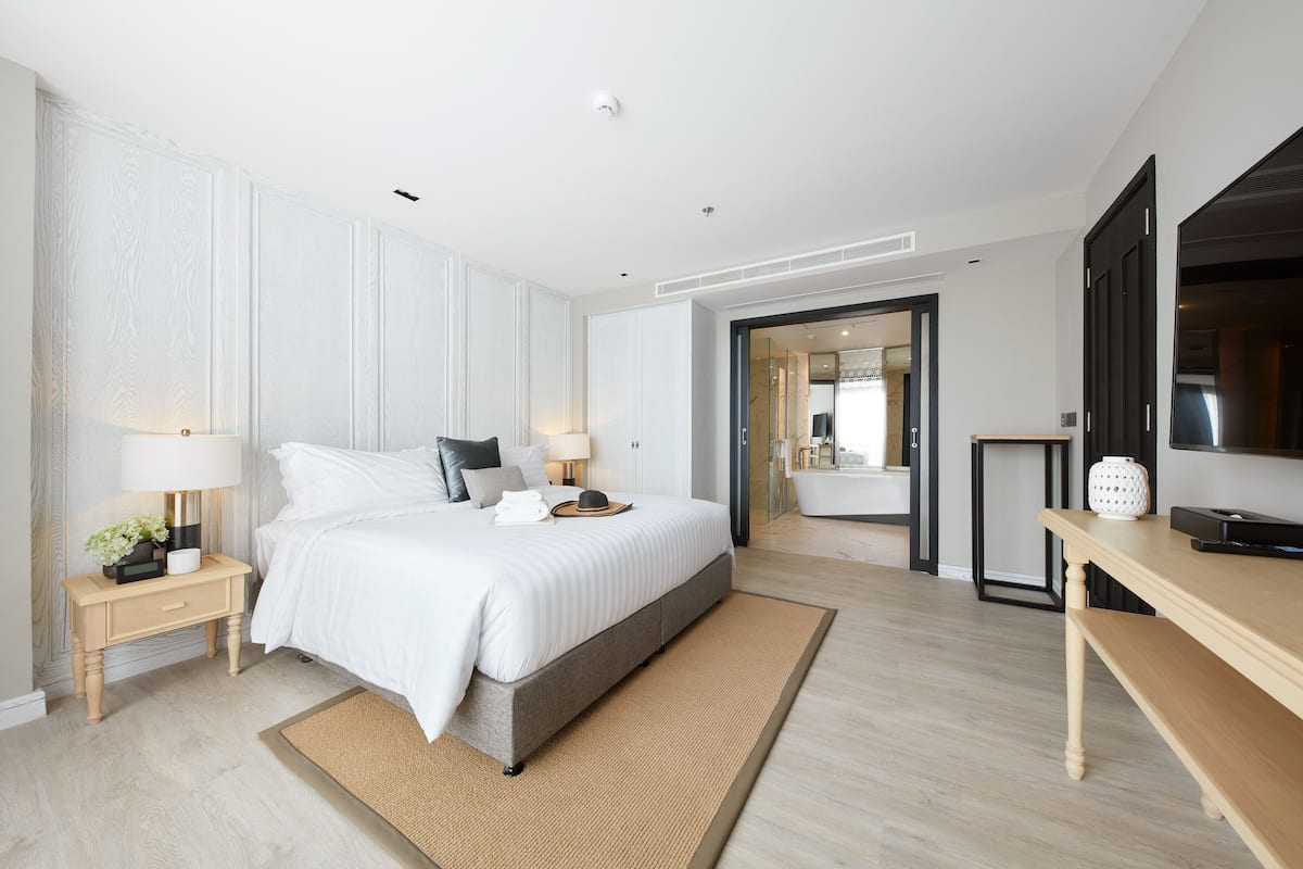 A modern bedroom with a large bed, bedside tables, a desk, and a television.