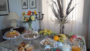 Una mesa con una variedad de alimentos, incluyendo un pastel, pasteles, frutas y bebidas, sobre un mantel de encaje.