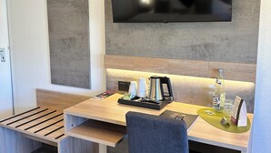 A modern kitchen with a large flat-screen TV mounted on the wall, wooden countertops, and a built-in bench with storage. - an Hotel (Selm)