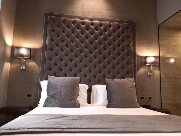 A hotel room with a tufted headboard, two bedside lamps, and a bed with pillows. - Forvm Luxury Experience - Dependance (Trieste)