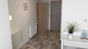 A hallway with a radiator, a wooden wardrobe, a door, and a small plant on a table. - Pension Lindenhof (Limburg an der Lahn)