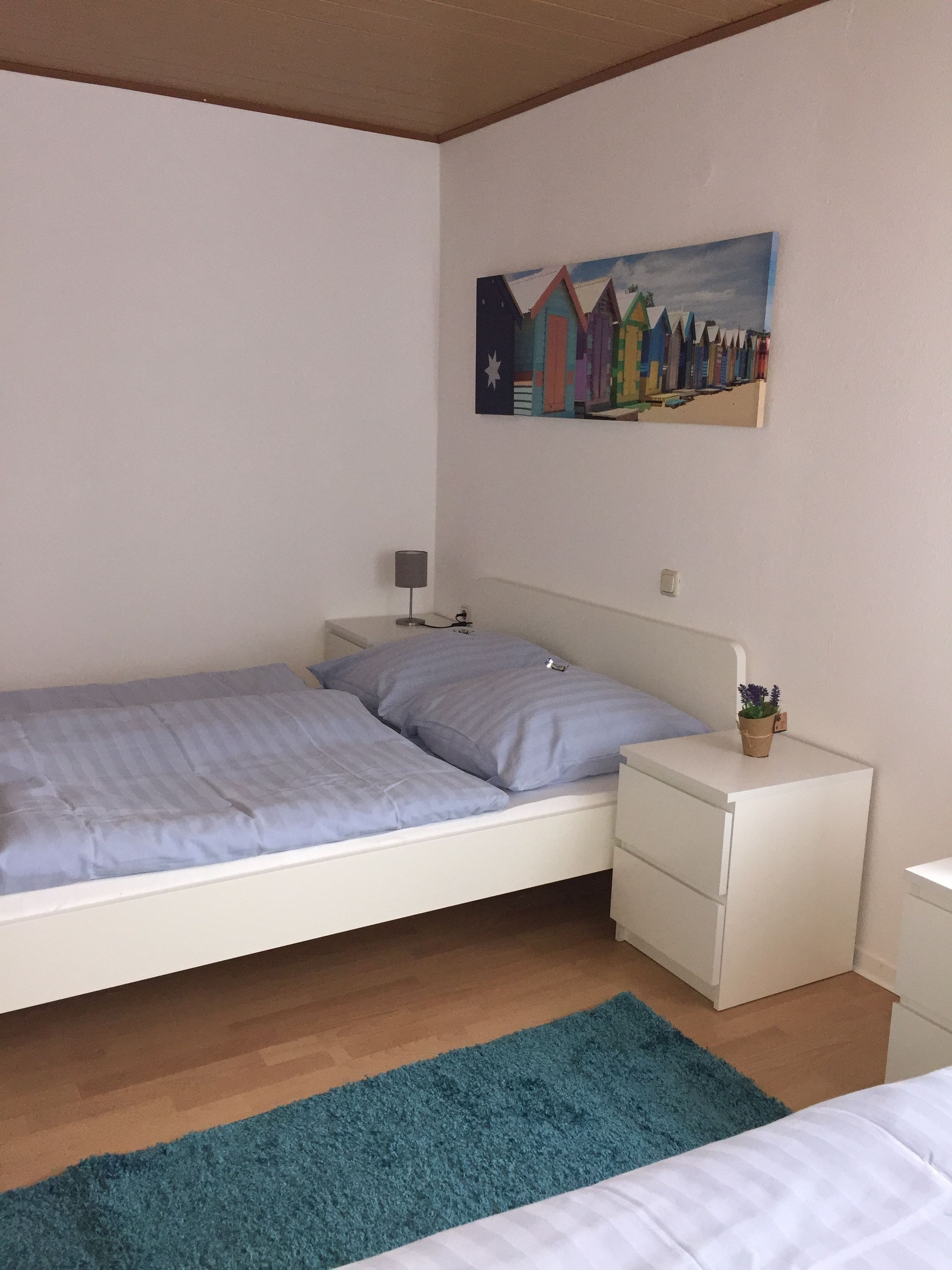 Un dormitorio con una cama individual, una mesita de noche, una lámpara y un cuadro en la pared.