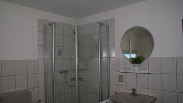 A bathroom with a glass-enclosed shower, a sink, and a mirror.