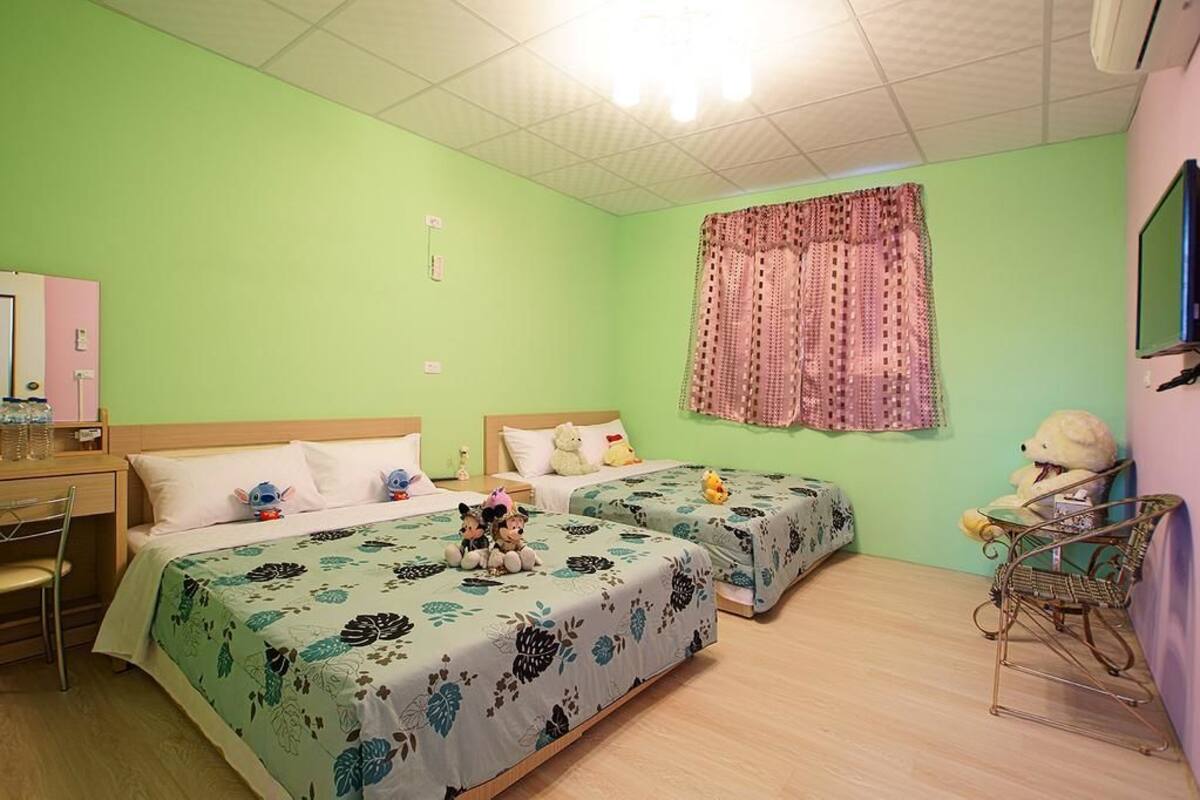 Una habitación con dos camas, un escritorio, una silla y una televisión.