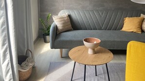 A modern living room with a grey sofa, a wooden coffee table, a yellow armchair, and a potted plant. - Ulika Rovinj Camping (Rovinj)