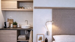A modern bedroom with a bed, bedside table, nightstand, and a wall-mounted lamp. - Ulika Rovinj Camping (Rovinj)