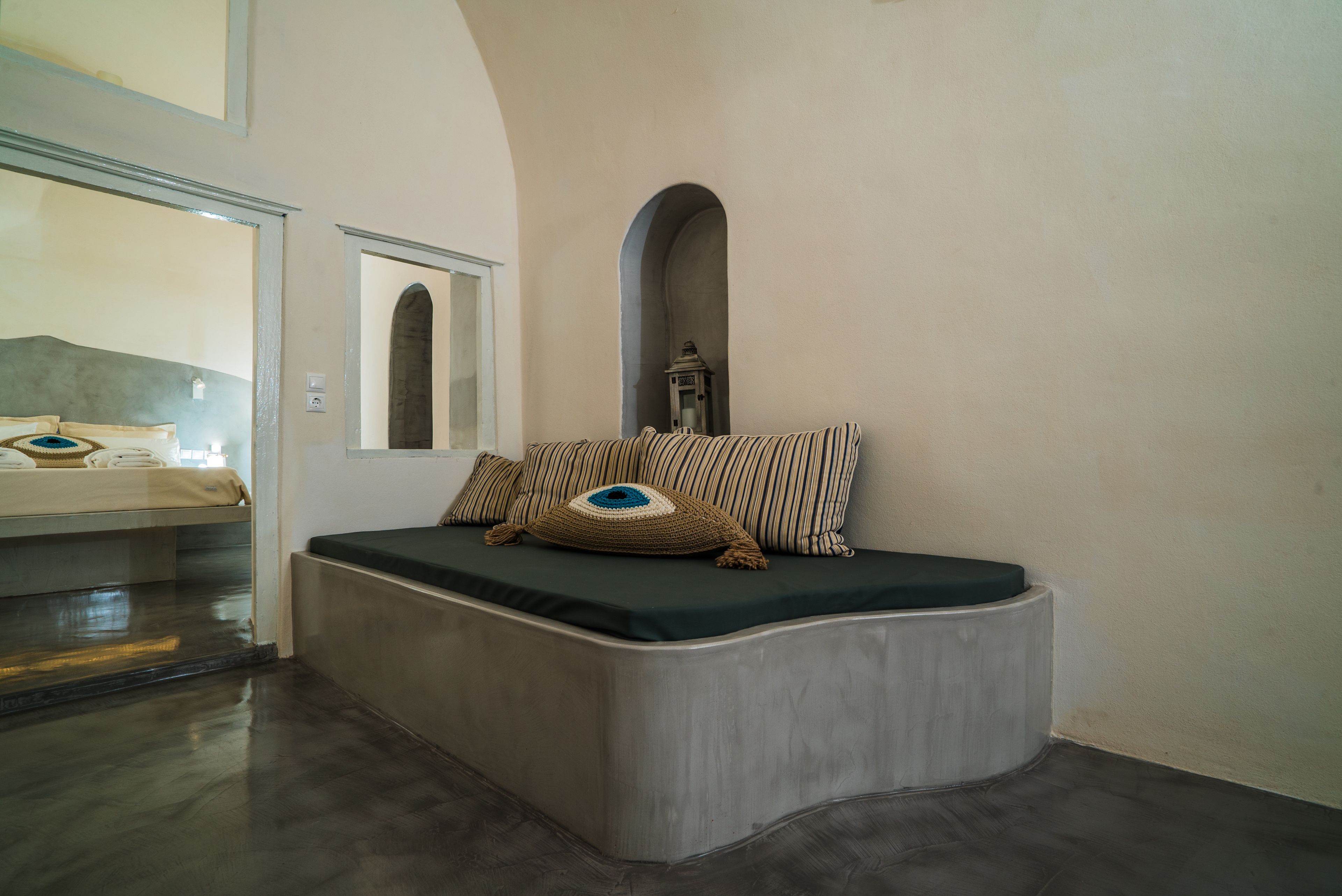 Une chambre à coucher moderne avec un lit aux lignes courbes, un miroir et une petite fenêtre en arc de cercle.