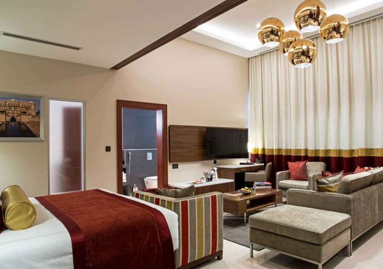 A hotel room with a bed, a sofa, a desk, and a TV.
