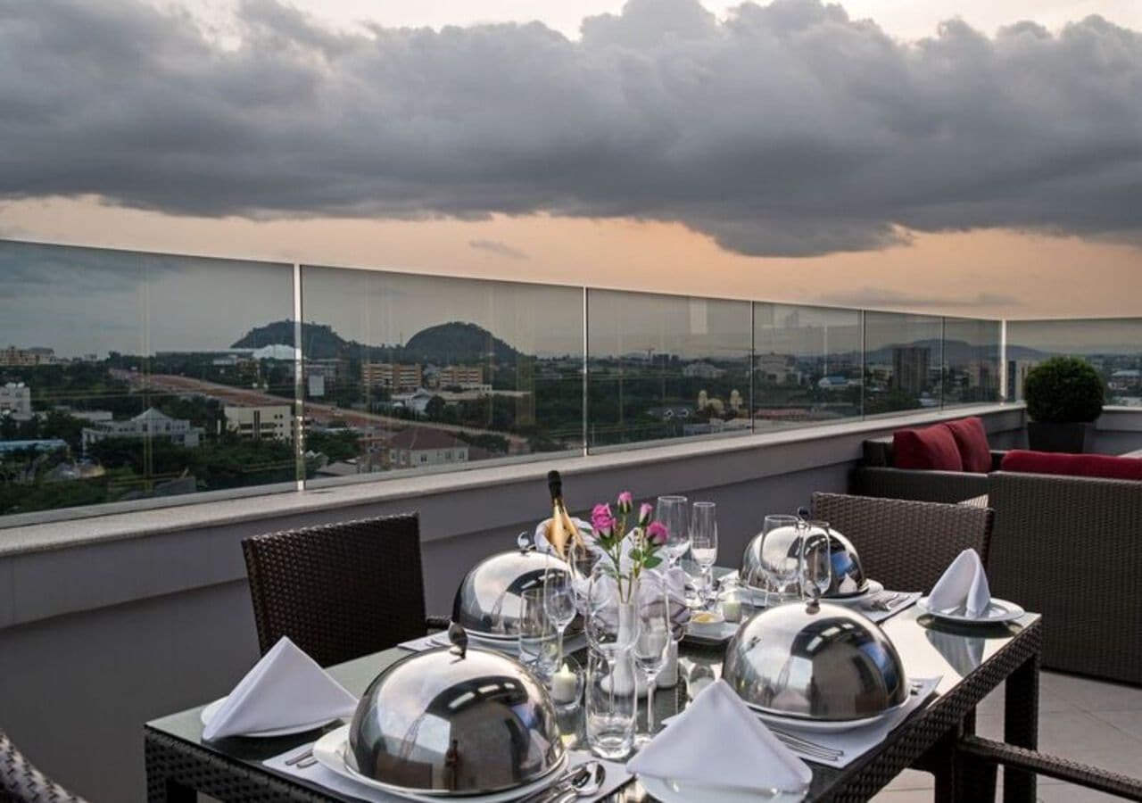 A table set for dining on a rooftop with a cityscape view.