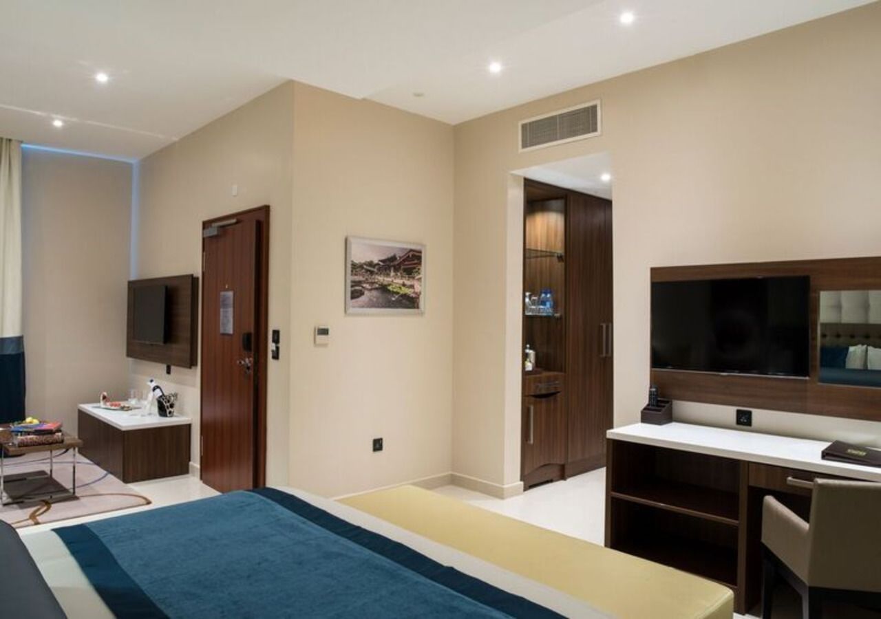 A modern hotel room with a bed, a desk, a TV, and a bathroom.